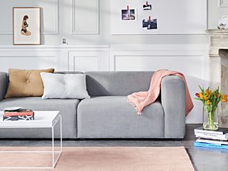 HAY grey ofa with pink blanket next to fireplace