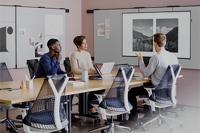 Stock image of 3 people meeting surrounded by Herman Miller office furniture